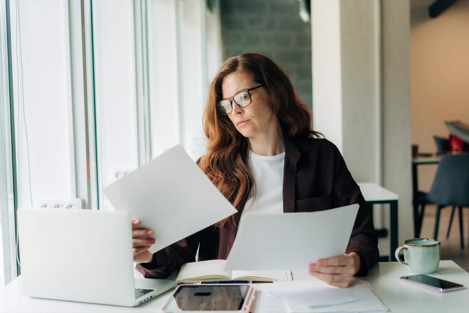 Profesional revisa documentación junto a su portátil en un espacio de trabajo